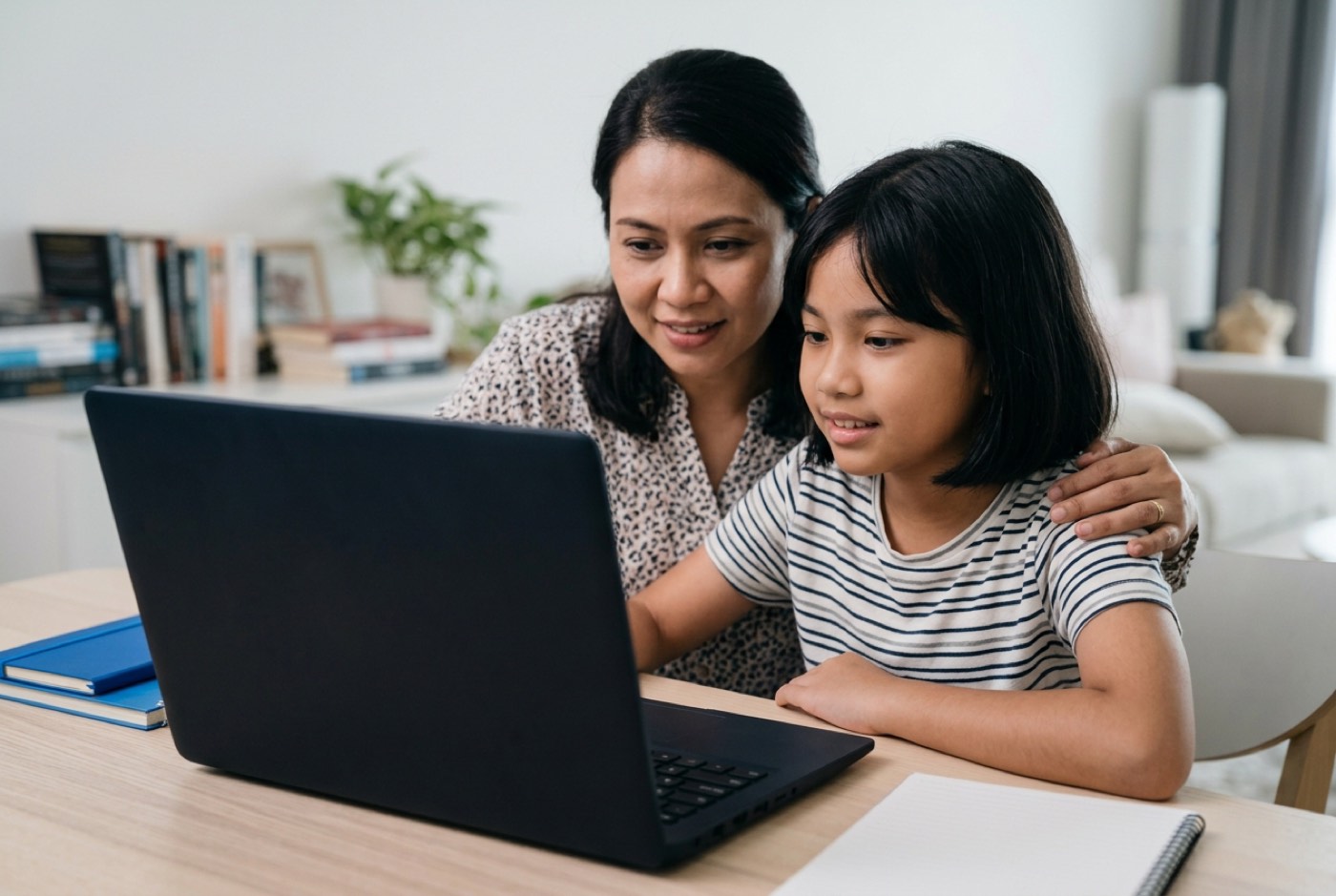 A parent and child sitting together at a computer desk reviewing digital privacy settings on screen in a modern livin...